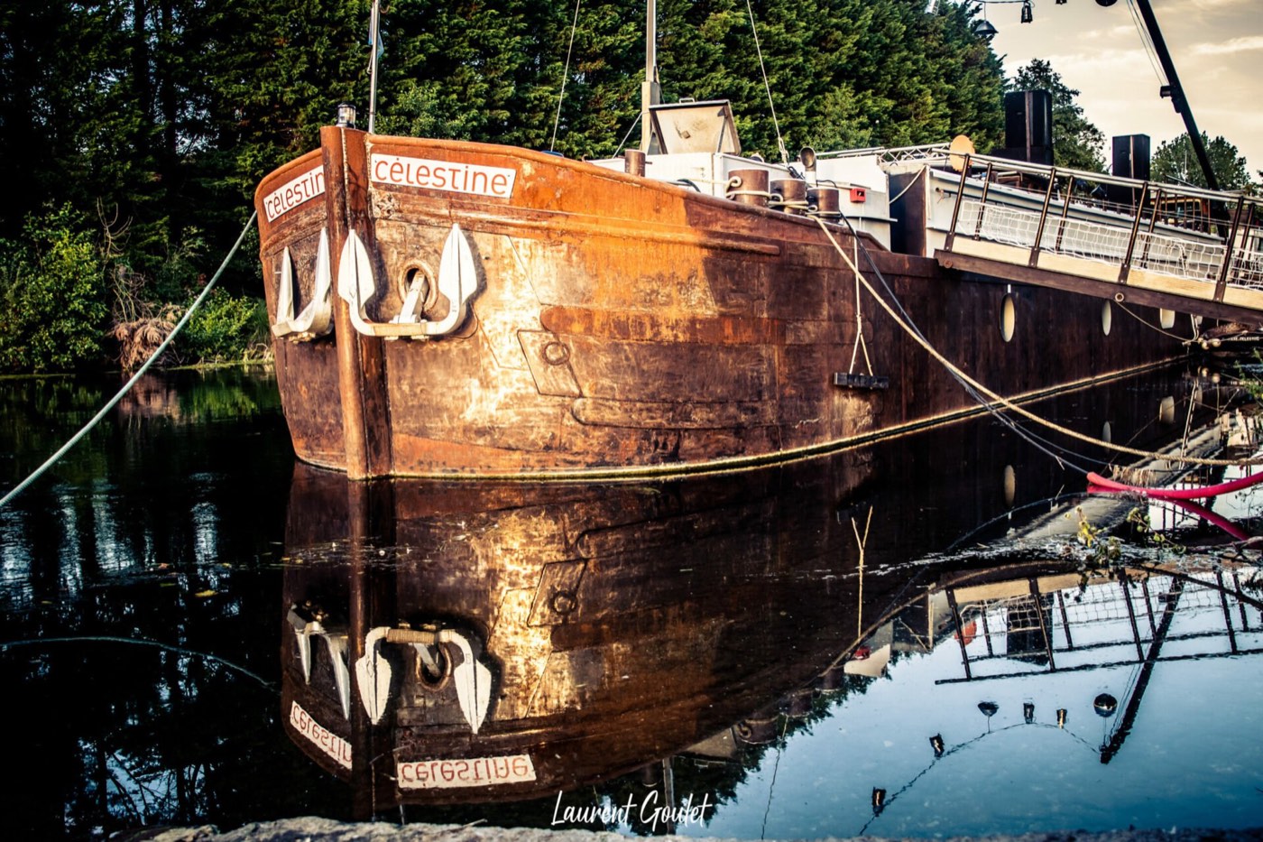 La péniche Célestine amarrée, sa coque rouillée se reflétant dans l'eau du canal